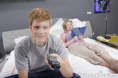 Young Man Watching TV In Bedroom