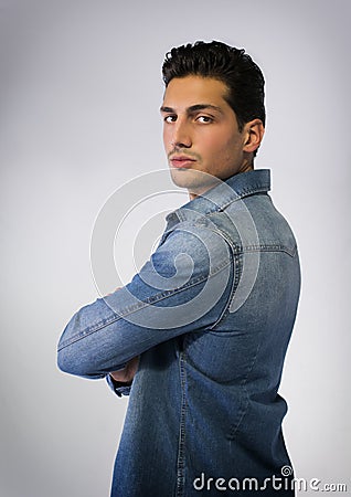 Young man wearing denim shirt, arms crossed on chest