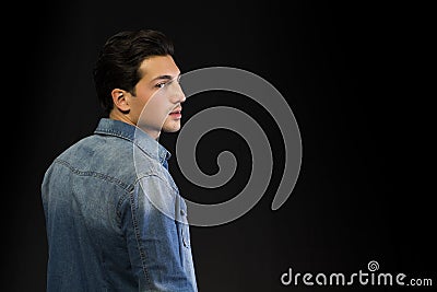 Young man wearing denim shirt seen from the back, looking to a side