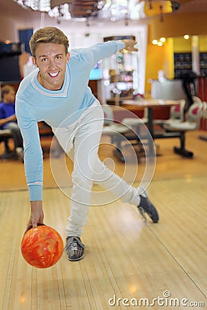 Young man wearing sweater throws ball in bowling