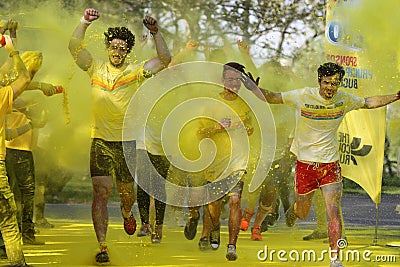 Young men running through yellow paint splatter