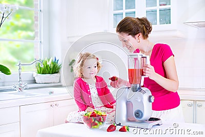 Young mother and daughter making fresh fruit jiuce