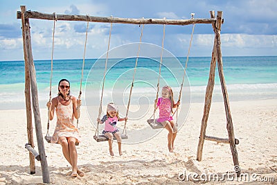 Young mother and her cute daughter swinging on a