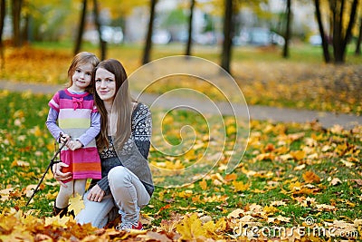 Young mother and her little daughter at fall