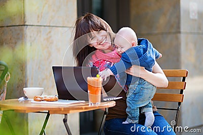 Young mother with little son working on her laptop