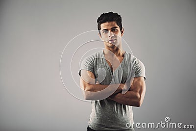 Young muscular man posing against grey background