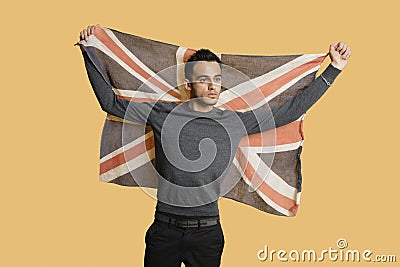 Young patriotic man lifting British flag over colored background