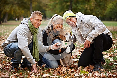 Young people with cute dog in park smiling