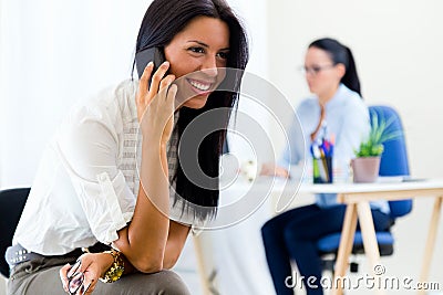 Young pretty business woman with mobile phone in her office.