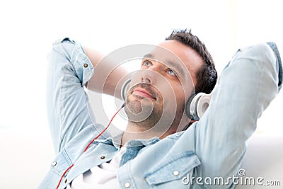 Young relaxed man listening music in a sofa