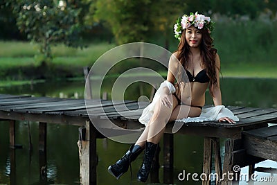 Young sexy Asian woman in black lingerie sitting on the wooden b