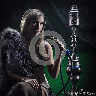 A young and sexy blond woman smoking a hookah