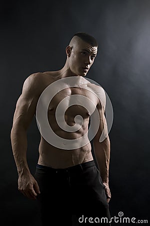 Young sexy man with athletic body on black background