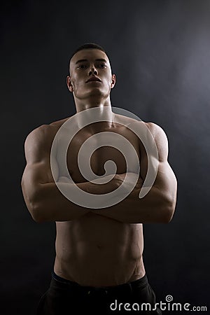 Young sexy man with athletic body on black background