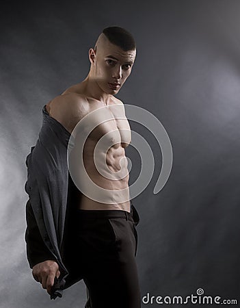 Young sexy man with athletic body on black background