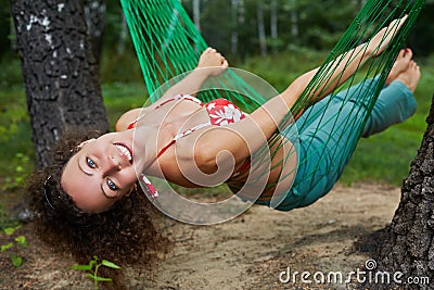 Young smiling barefooted woman swing in hammock