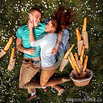 Young smiling couple lying and dreaming on the grass with basket
