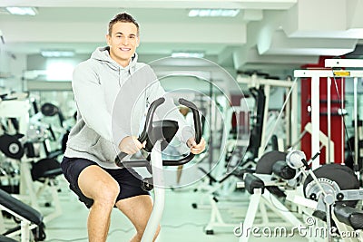 Young smiling man in a gym, exercising his legs doing training