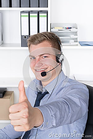 Young smiling man with headset is showing thumb up