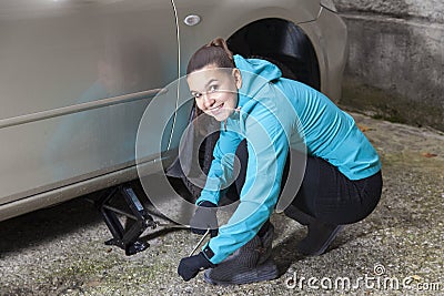 Young smiling woman driver changes car tyres