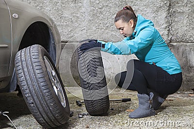 Young smiling woman driver replacing tires