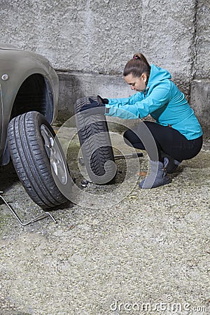 Young smiling woman driver replacing tires