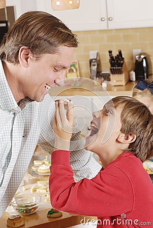 Young son feeding dad a cookie in the kitchen