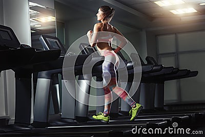Young sporty woman run on machine in the gym