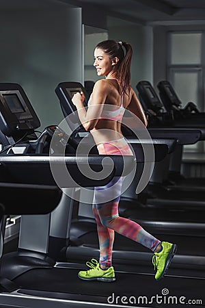Young sporty woman run on machine in the gym