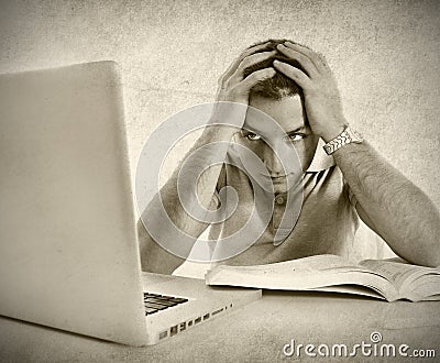 Young student man in stress overwhelmed studying exam with book and computer