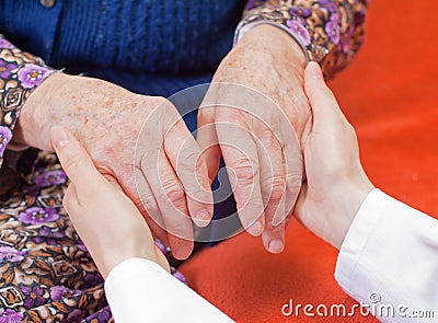 Young sweet doctor holds the old woman s hand