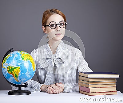 The young teacher in glasses with books and globe