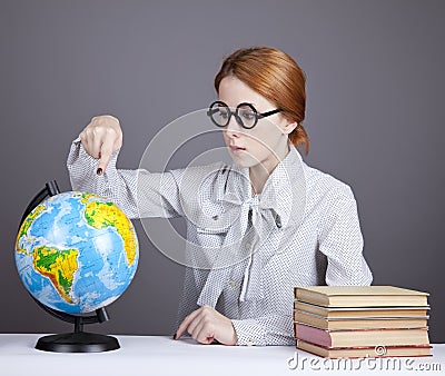 The young teacher in glasses with books and globe