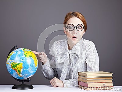 The young teacher in glasses with books and globe