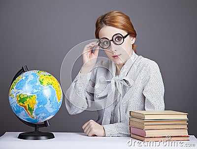 The young teacher in glasses with books and globe