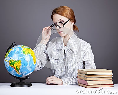 The young teacher in glasses with books and globe