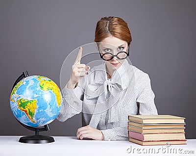 The young teacher in glasses with books and globe