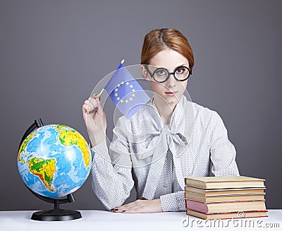 The young teacher in glasses with books and globe