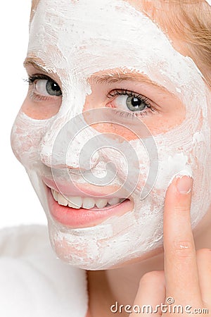 Young teen girl putting facial mask cream