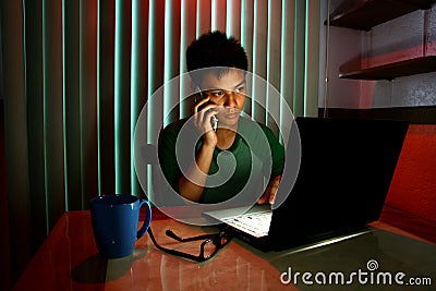 Young Teen using a cellphone or smartphone in front of a laptop computer