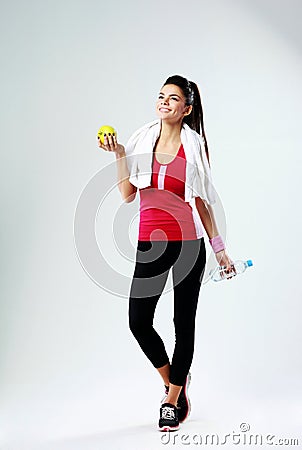 Young thoughtful happy sport woman with apple and bottle of water