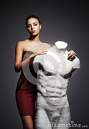 A young woman in a beautiful dress posing with a mannequin