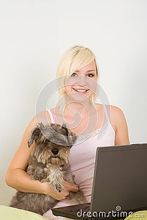 Young woman in bed with laptop and schnauzer dog