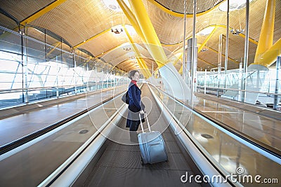 Young woman with big travel bag stands in hallway