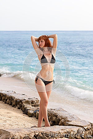 Young woman in bikini posing on sea coast