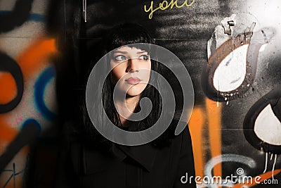 Young woman in black coat at the graffiti wall