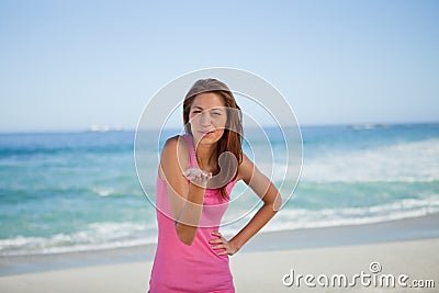 Young woman blowing an air kiss on the beach