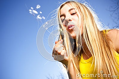 Young woman blowing dandelion