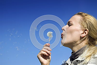 Young woman blowing dandelion seeds