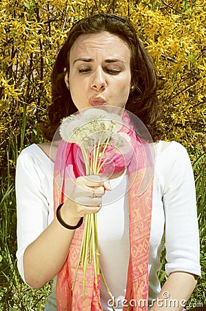 Young woman blowing on dandelions